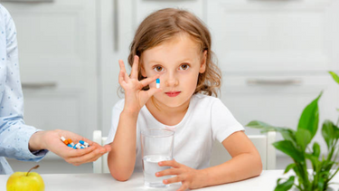 Child taking daily multivitamin before school